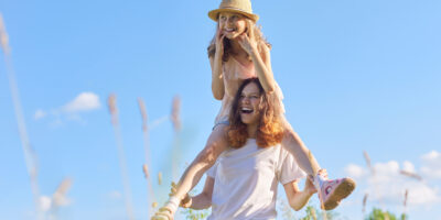 Happy laughing children playing in meadow, two sister girls having fun in nature