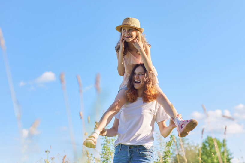 Happy laughing children playing in meadow, two sister girls having fun in nature