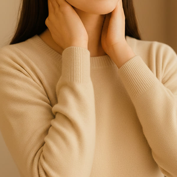 両手を首元に添えている女性